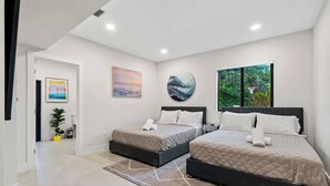 A modern bedroom with two beds, a large window with a view of greenery, and artwork on the walls. - One and Only Lazy River Pool Villa (Miami)