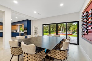 Enjoy meals around a spacious dining table surrounded by six chairs, with a view of the lush outdoor area.