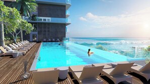 Un área junto a la piscina con sillones, una piscina y vista al océano.