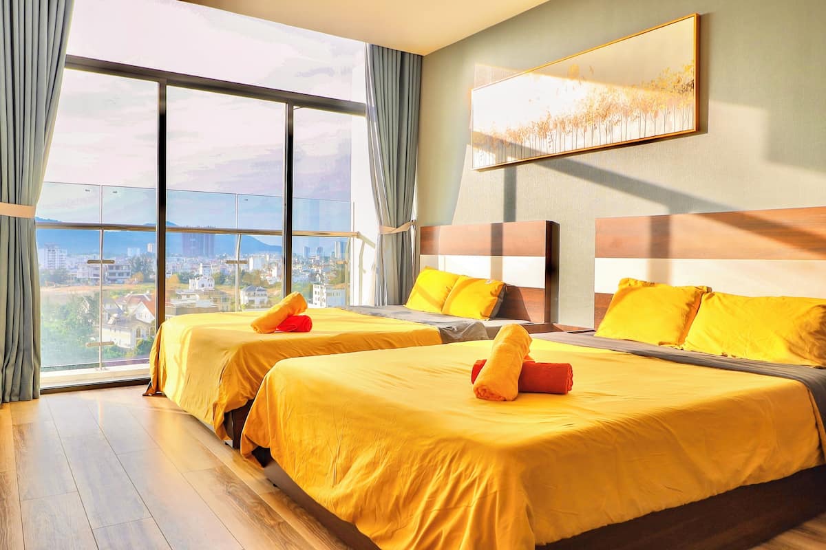Une chambre d’hôtel avec deux lits, de grandes fenêtres et une vue sur la ville.