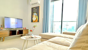 Een moderne woonkamer met een flatscreen-tv waarop 'Netflix' staat, een bank, een klein rond tafeltje met een boek, een decoratieve vaas, en een poster van een kat met parel oorbellen.