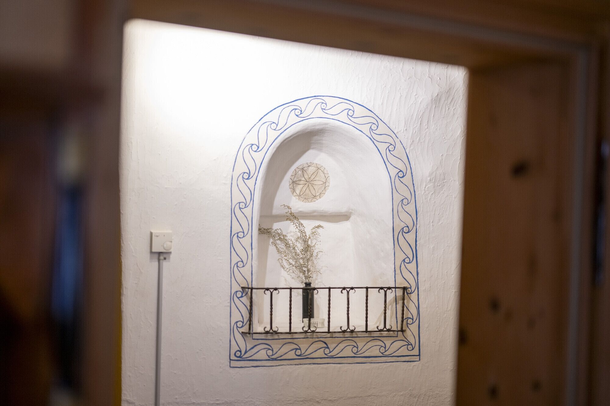 A door with a decorative arch and a small window with a metal grille.