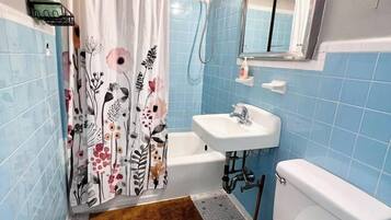 A bathroom with a shower curtain, a toilet, a sink, and a mirror.