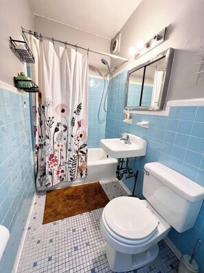 A bathroom with a shower curtain, a toilet, a sink, and a mirror.