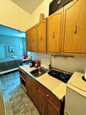 A compact kitchen with wooden cabinets, a sink, a stove, and a refrigerator.