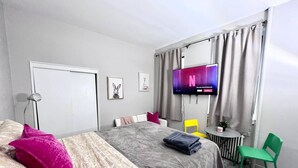 Ein Schlafzimmer mit einem Bett, einem Fernseher, einem Schreibtisch und einem Sessel.