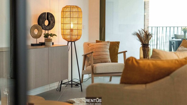 A modern living room with a sofa, a floor lamp, and decorative items on a shelf.
