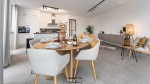 A modern kitchen with built-in appliances, a dining area with a round table and chairs, and a cozy seating area with a lamp.