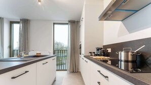 A modern kitchen with white cabinets, a black countertop, and a large window with curtains.