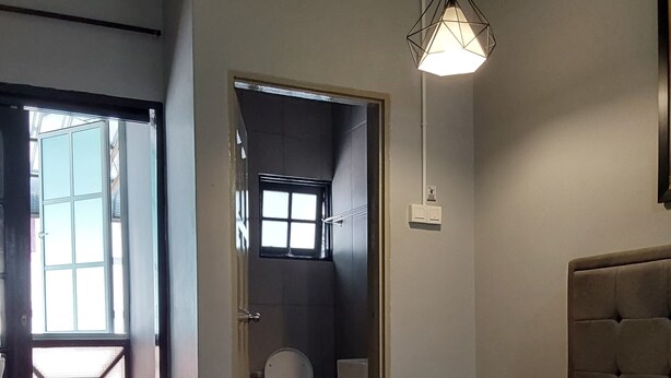 A hotel room with a bed, a window, a door, and a hanging light fixture. - Bricks Cameron Hostel (Tanah Rata)