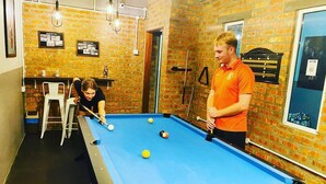 A pool table in a room with brick walls and a window. - Bricks Cameron Hostel (Tanah Rata)