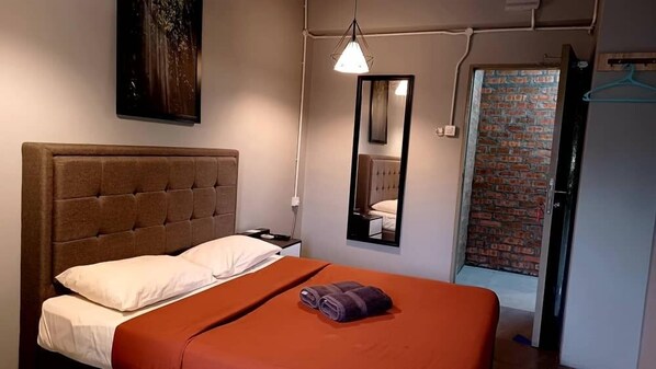 A hotel room with a large bed, a nightstand, a mirror, and a hanging light fixture. - Bricks Cameron Hostel (Tanah Rata)