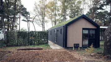 A modern, single-story building with a sloped roof, large windows, and a small porch area.