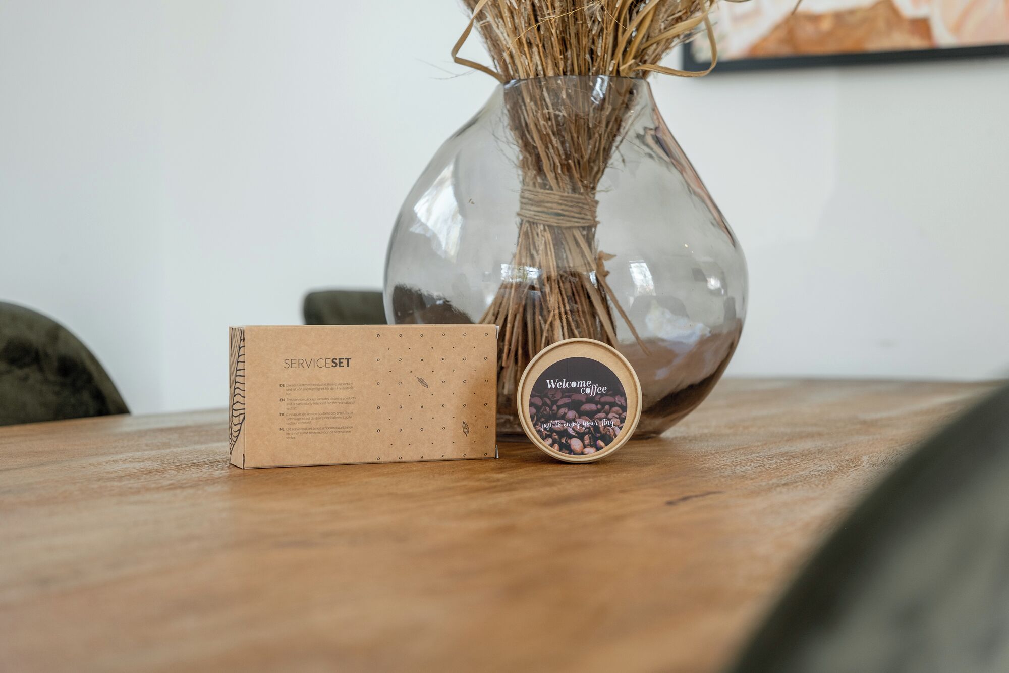 Eine Glasvase mit Trockenpflanzen, eine Setzkasten-Box und eine runde Dose mit Kaffee-Etikett.