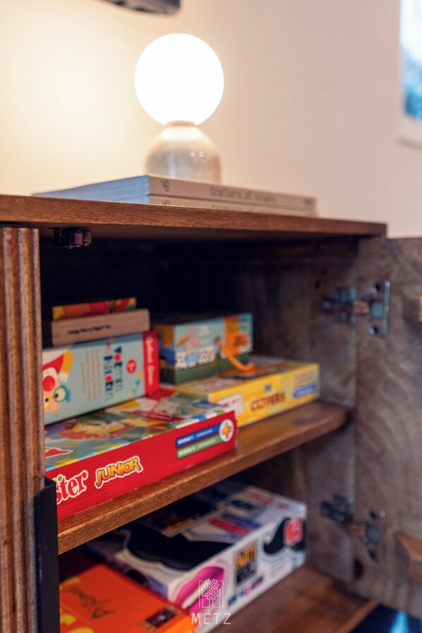 Une étagère en bois avec divers jeux de société et une lampe.