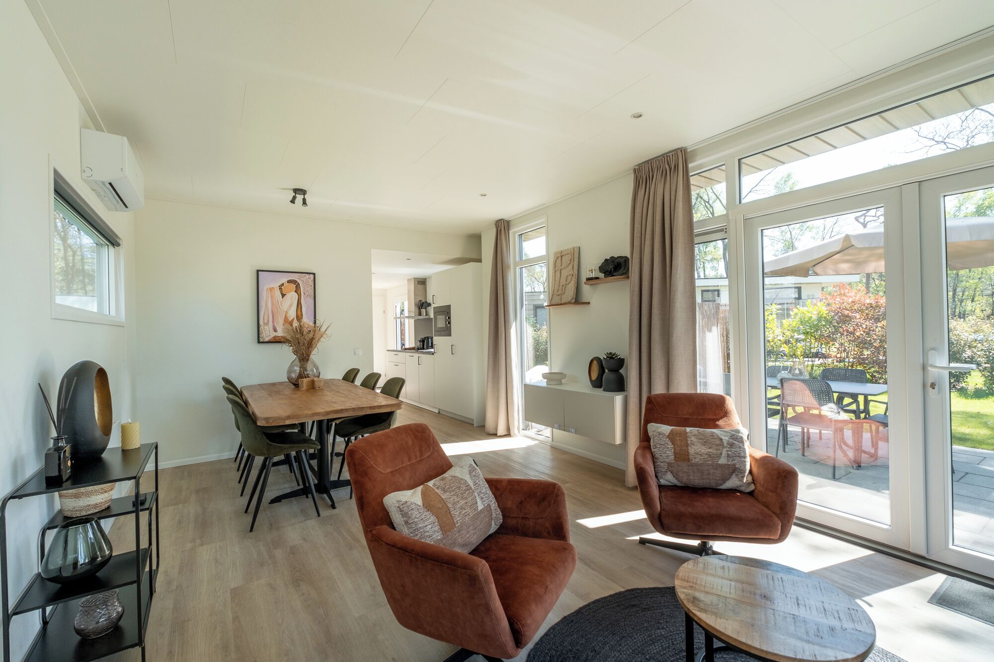 A modern living room with a dining area, large windows, and a view of the outdoors.