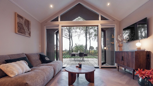 Un salon moderne avec un canapé, une table basse et un téléviseur posé sur un meuble en bois.