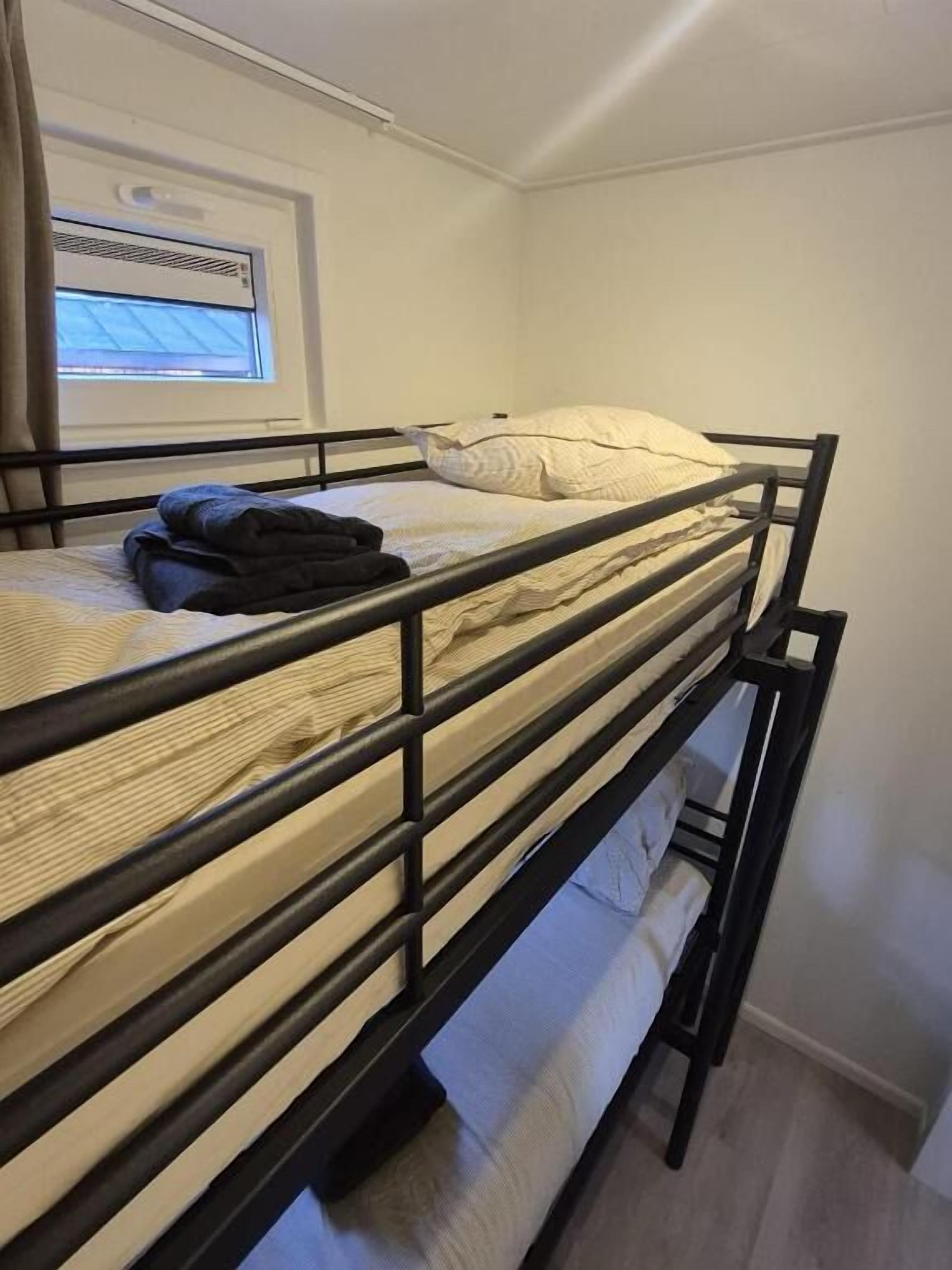 Un lit superposé avec une fenêtre, un radiateur et un rideau.