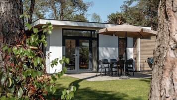 Una casa moderna con un patio, mobiliario exterior y una zona cubierta.