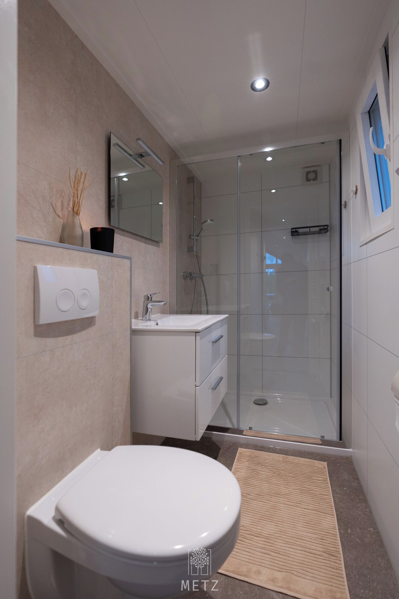 A modern bathroom with a toilet, sink, and glass shower enclosure.