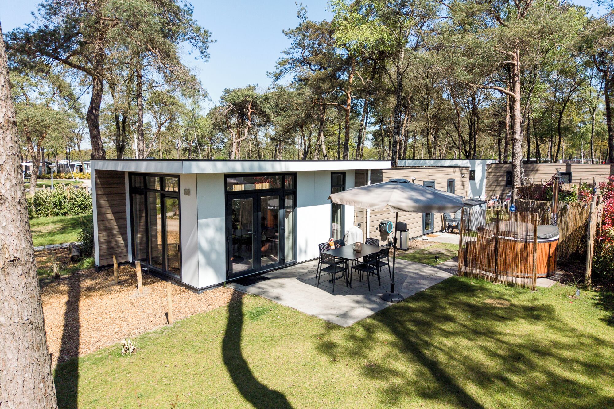 Un patio exterior moderno con una mesa y sillas, rodeado por una valla de madera y árboles.