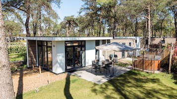 Un patio exterior moderno con una mesa y sillas, rodeado por una valla de madera y árboles.
