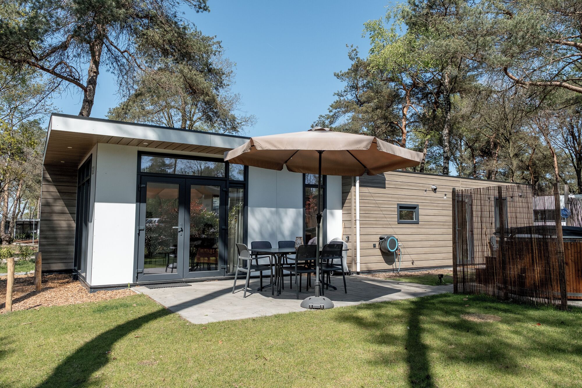 A modern house with a patio, a dining table, and chairs.