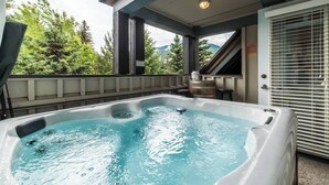 Ein Whirlpool mit Bergblick, ein Holzfass und ein Barhocker.