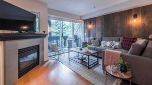Ein modernes Wohnzimmer mit Kamin, Sofa, Couchtisch und Fernseher.