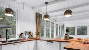 Een moderne keuken met witte kasten, een houten aanrechtblad en hanglampen.