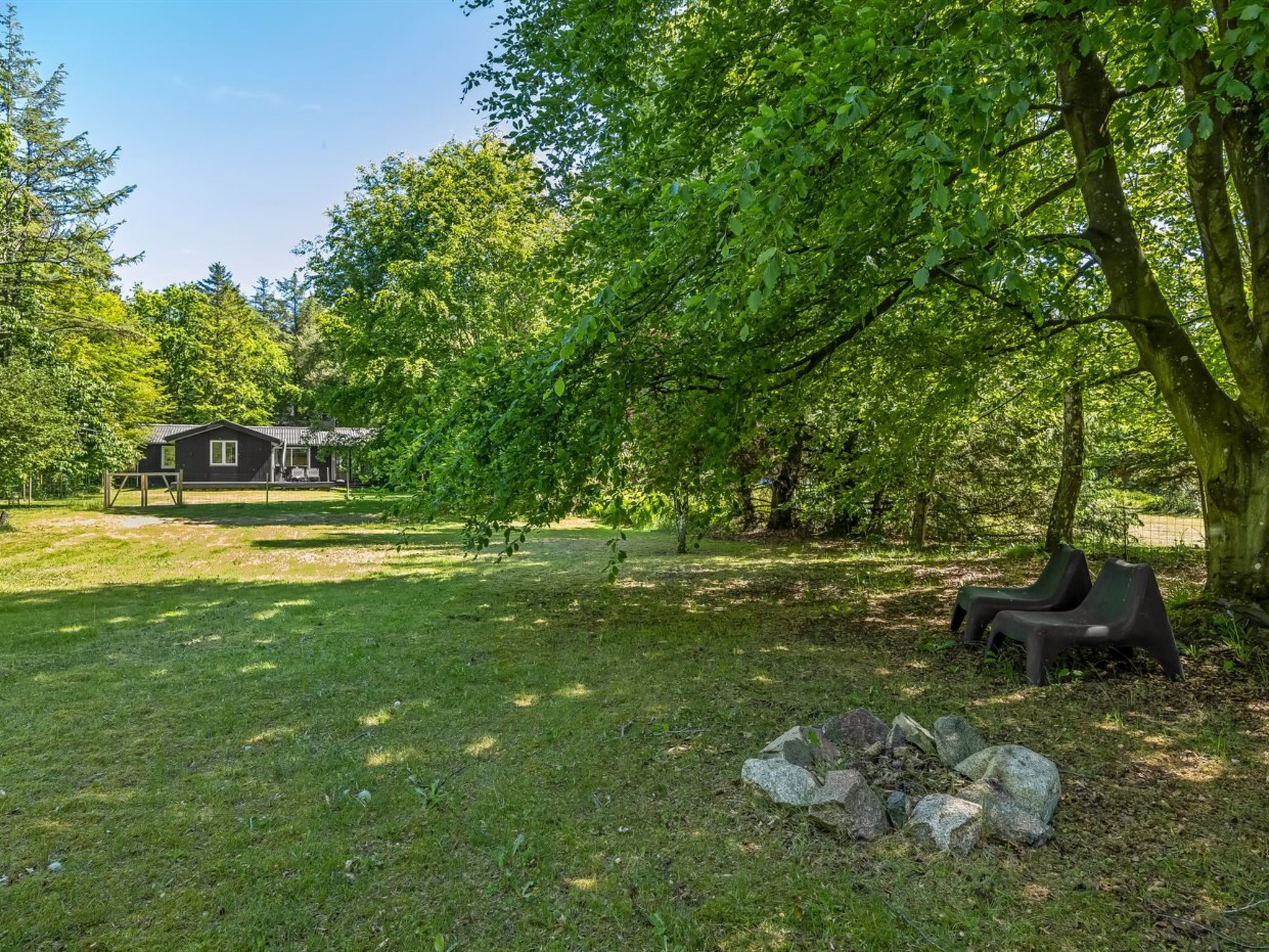A grassy area with a small building, trees, and outdoor seating.