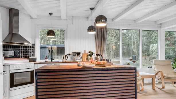 Een moderne keuken met een groot eiland, witte kasten en uitzicht op de omgeving.