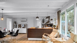 Een moderne keuken met een centraal kookeiland, houten vloeren en hanglampen.