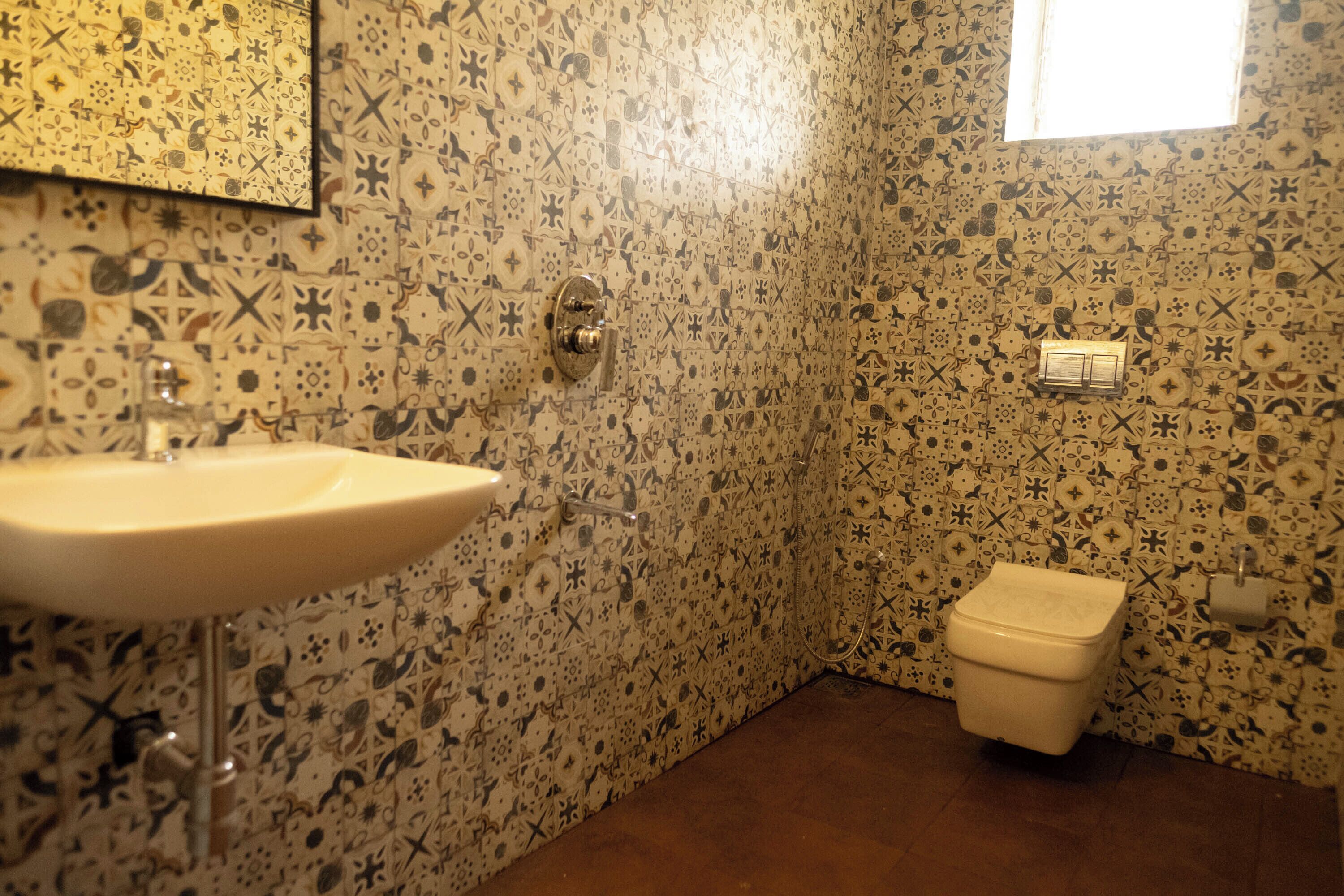 A bathroom with a sink, toilet, and patterned walls.