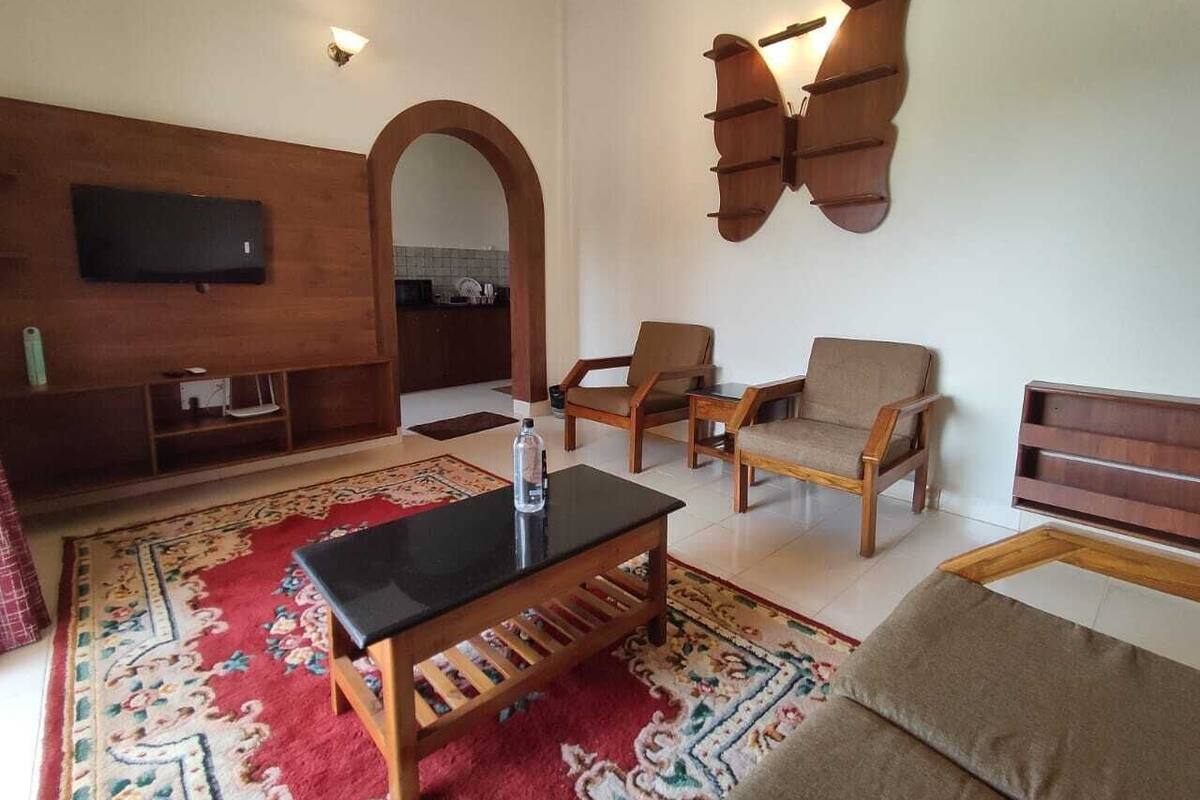 Un salon avec un téléviseur fixé à un mur en bois, un canapé, deux fauteuils, une table basse et un élément décoratif mural.