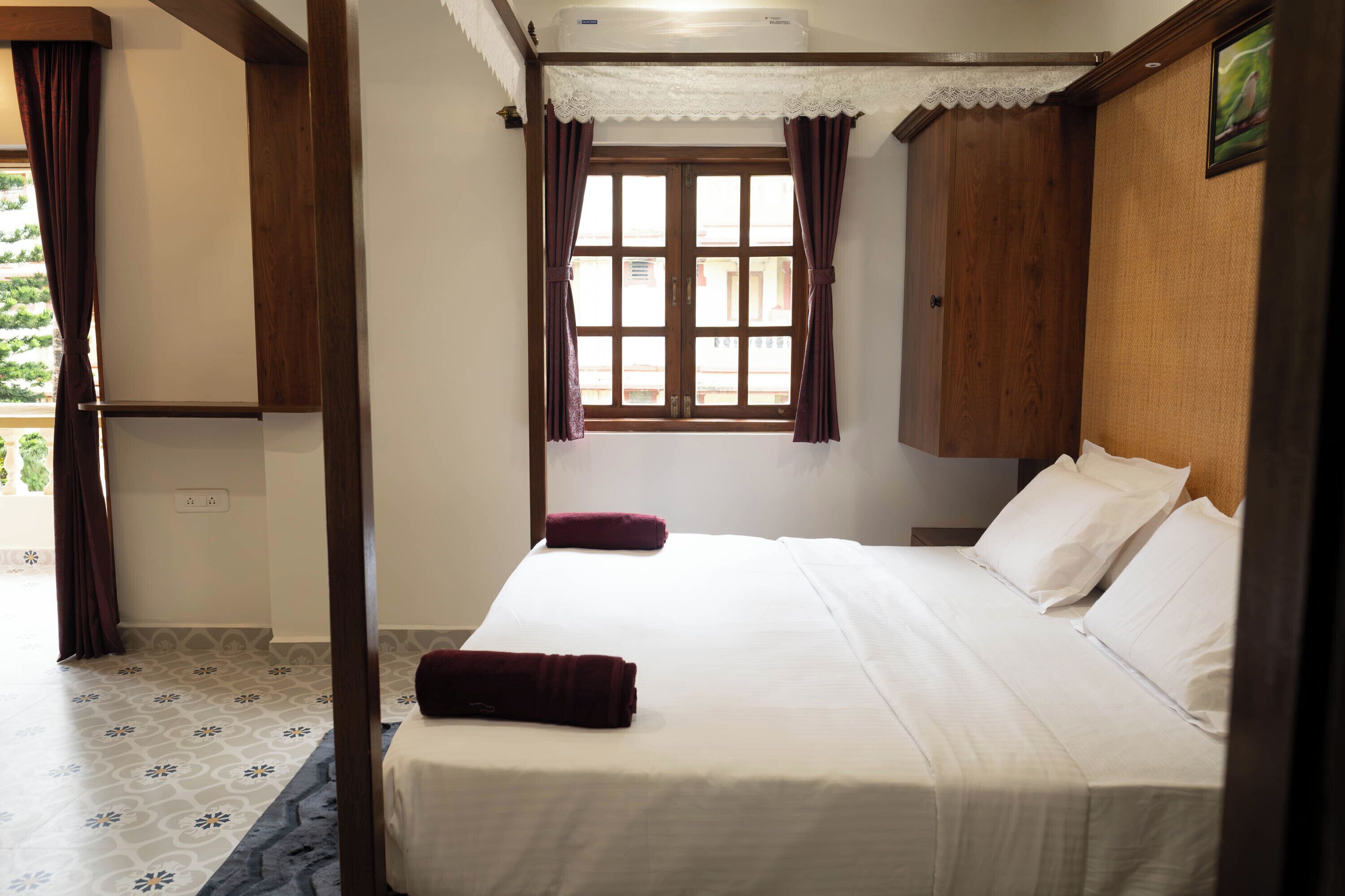 Un dormitorio con una cama, una ventana con cortinas y un armario de madera.
