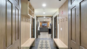 Ein Hotelkorridor mit Schließfächern, einer Rezeption und einem Bildschirm.