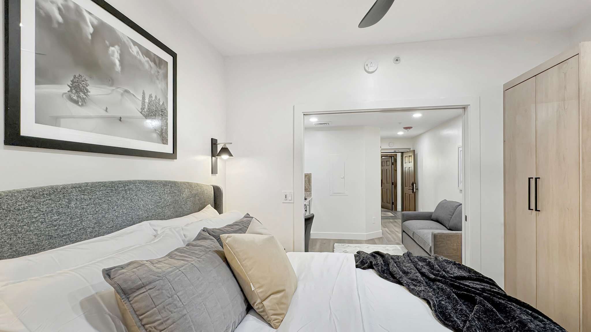 A hotel room with a bed, a bedside lamp, a framed picture on the wall, and a wardrobe.