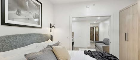 Habitación de hotel con cama, lámpara de noche, un cuadro en la pared y un armario.