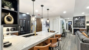 A modern kitchen with a marble countertop, stainless steel appliances, and pendant lighting.