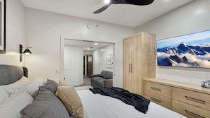 Ein modernes Schlafzimmer mit einem Bett, einem Fernseher, einem Kleiderschrank und einem Deckenventilator.