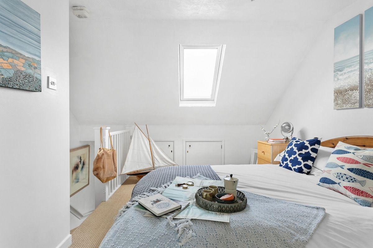 A bedroom with a bed, a window, a nightstand, and a sailboat model.