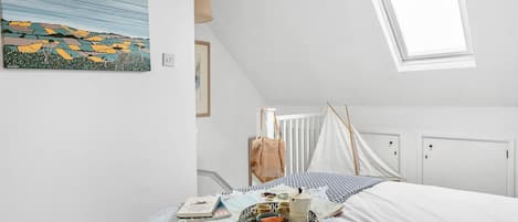 A bedroom with a bed, a window, a painting, and a bedside table with items.