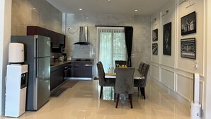 Eine moderne Küche mit Kühlschrank, Herd und Mikrowelle. Ein Essbereich mit Tisch und Stühlen ist ebenfalls vorhanden.