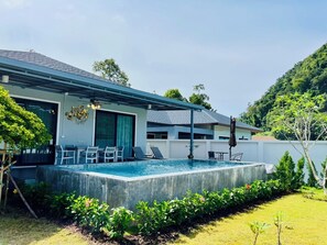 Une maison moderne dotée d’une piscine, d’un espace salon extérieur et d’une végétation luxuriante.