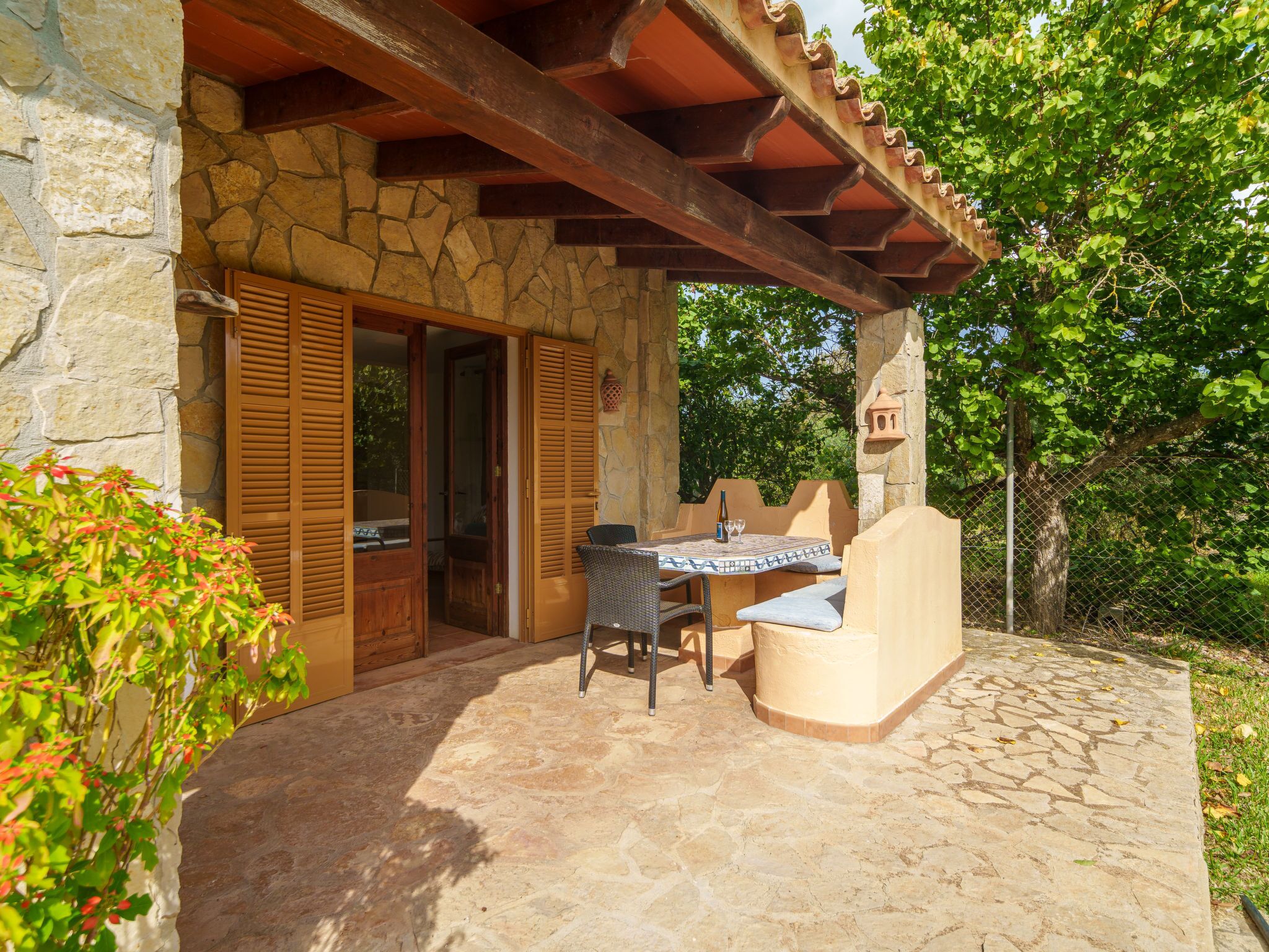 An outdoor patio with stone flooring, a table with chairs, and a wooden door.