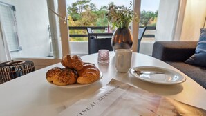 Una mesa con croissants, un florero con flores, una taza y un plato con una cuchara. Un menú con el título 