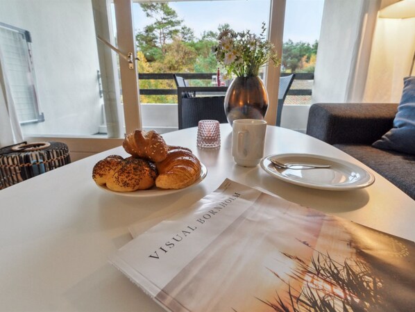 Una mesa con croissants, un florero con flores, una taza y un plato con una cuchara. Un menú con el título 