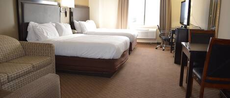 Quarto de hotel com duas camas, uma escrivaninha, uma cadeira e uma televisão.