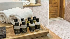 Un baño con tocador de madera, un perchero, un estante con artículos de aseo y una puerta de madera.